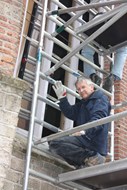 Jan Hoebe uit ’t Veldt ook glazenier helpt mee bij het inzetten van het raam