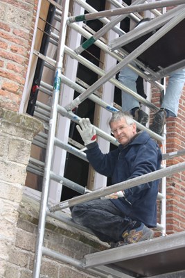 Jan Hoebe uit ’t Veldt ook glazenier helpt mee bij het inzetten van het raam