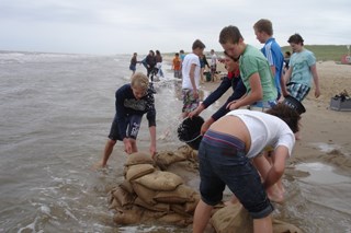 Met zandzakken een stukje strand inpolderen. Oefening baart kunst.